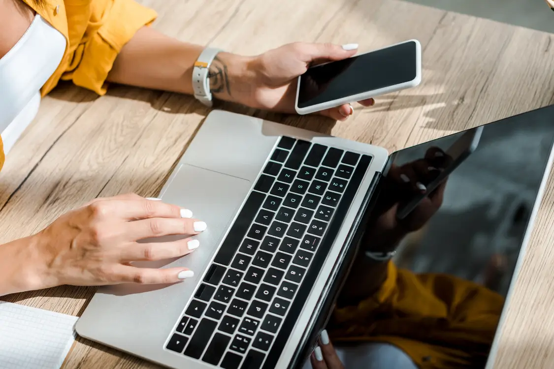 Woman using laptop and smartphone at desk